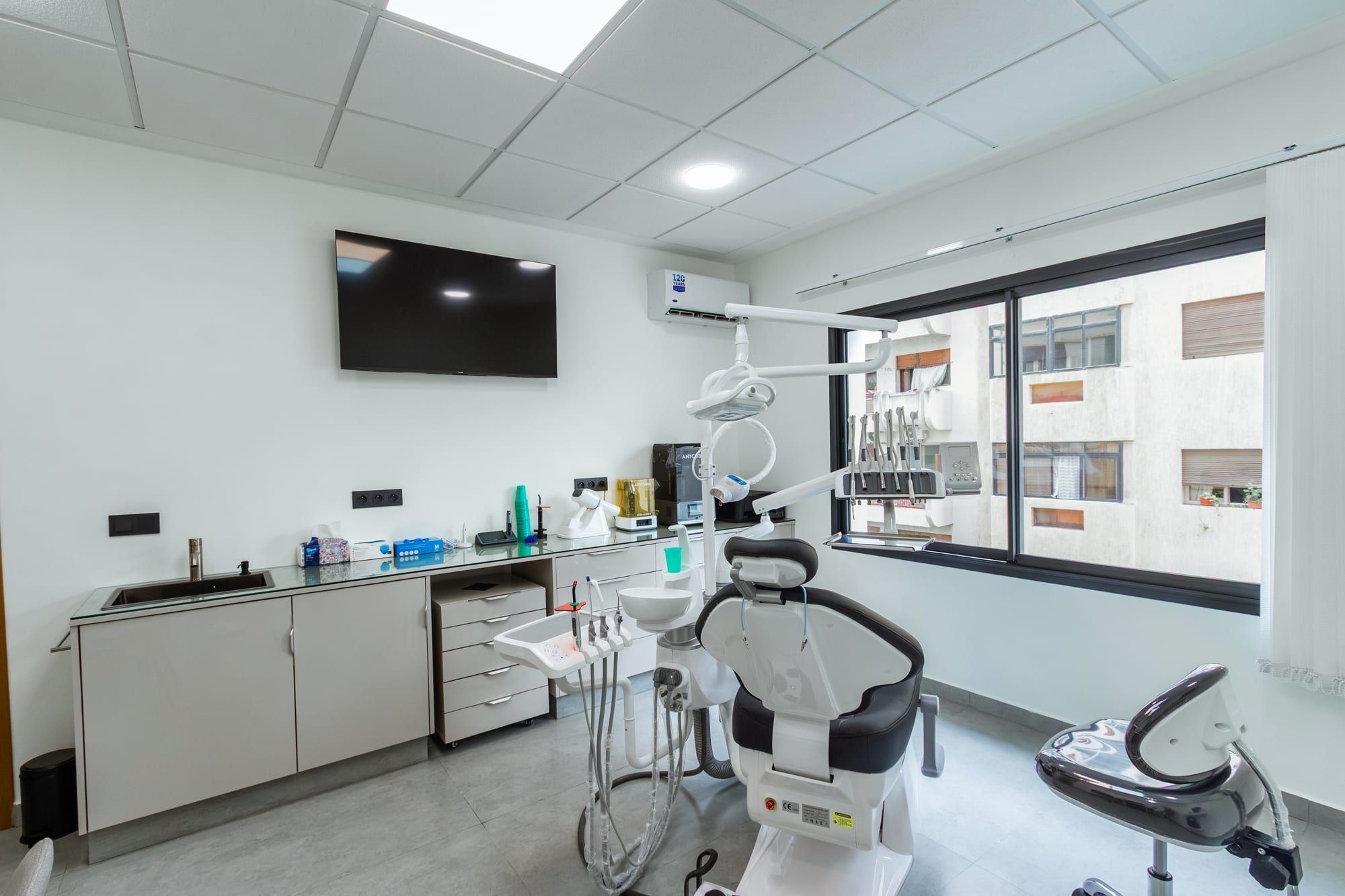 Salle de soins lumineuse avec le fauteuil dentaire face à la fenêtre